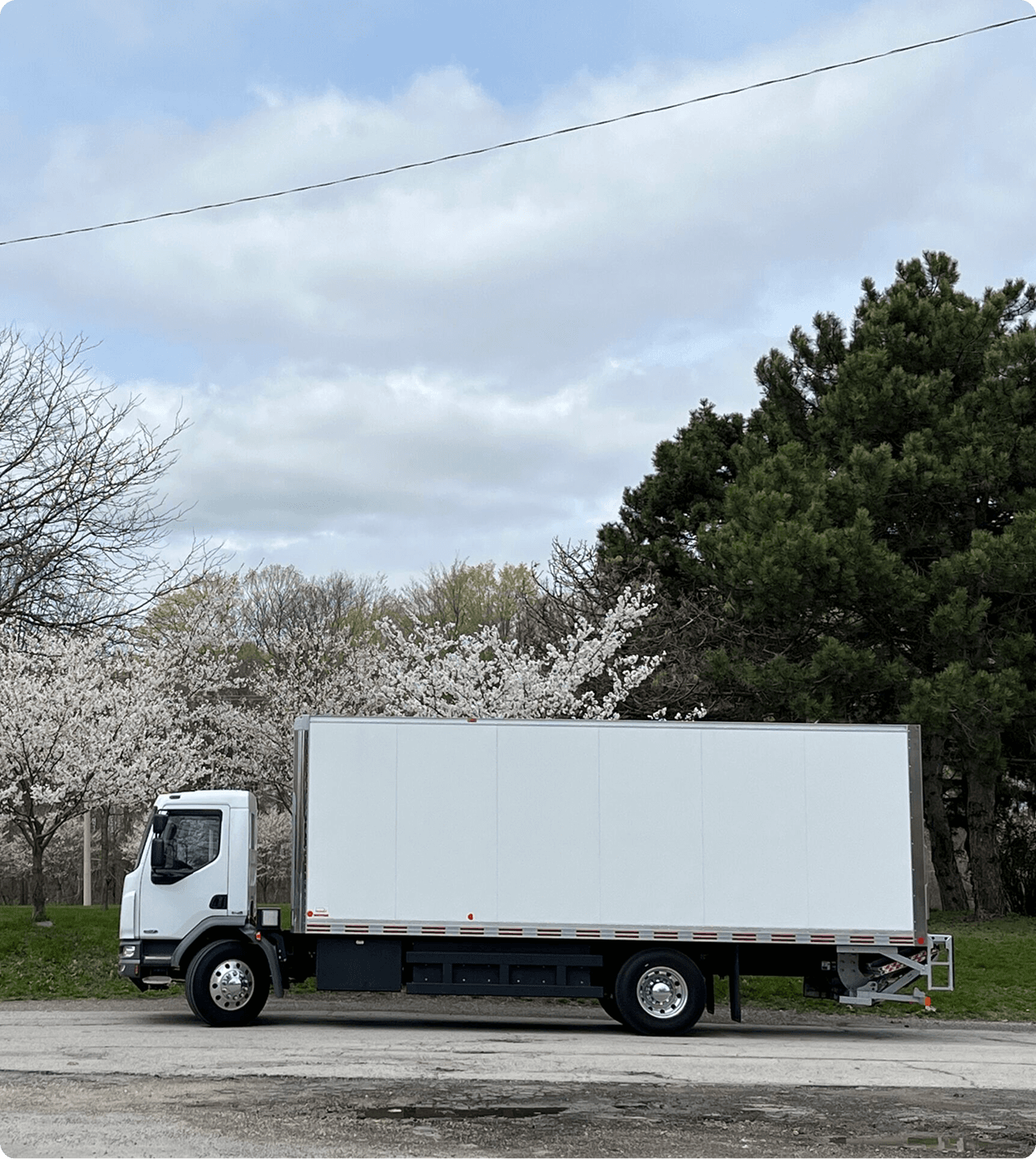 White box truck parked near trees